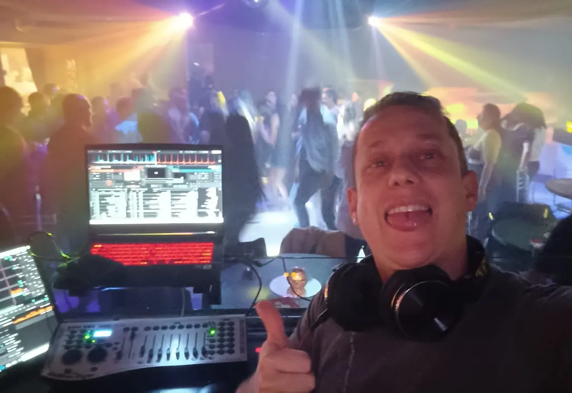 DJ Felipe Diniz da Svara Eventos na cabine com pista de dança cheia e iluminação com moving beam